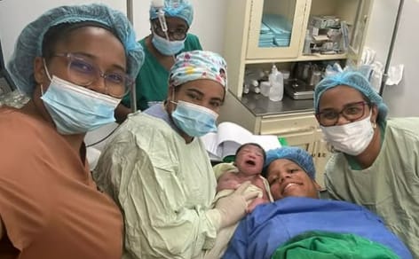 Equipo médico en la sala de partos junto a una madre y su recién nacido.